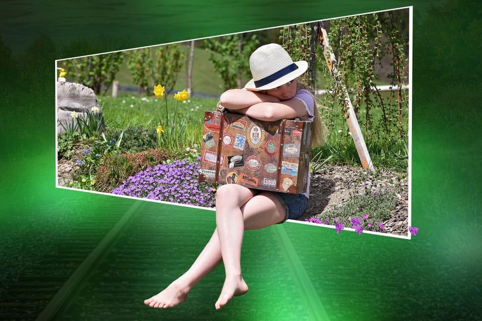 A child with suitcase sitting in flowers