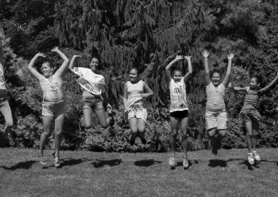 black and white photo of eight kids in a line in mid air from jumping