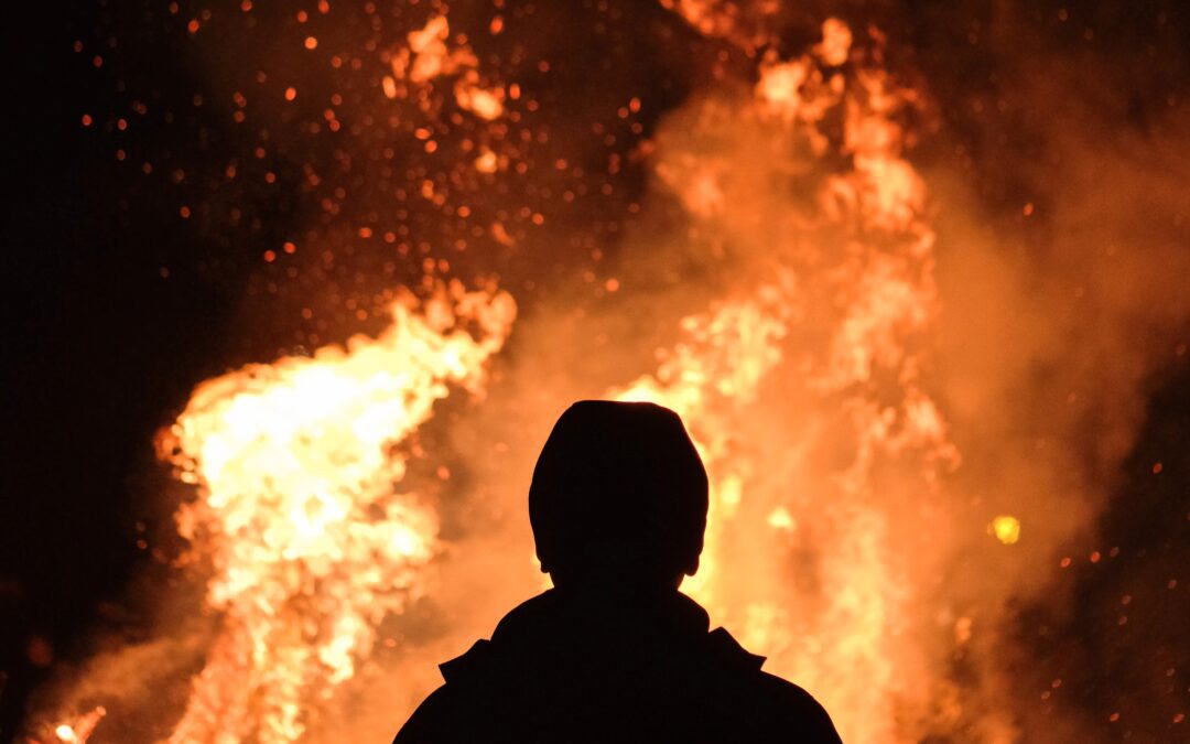 Wild fire with silhouette of man in front of fire.