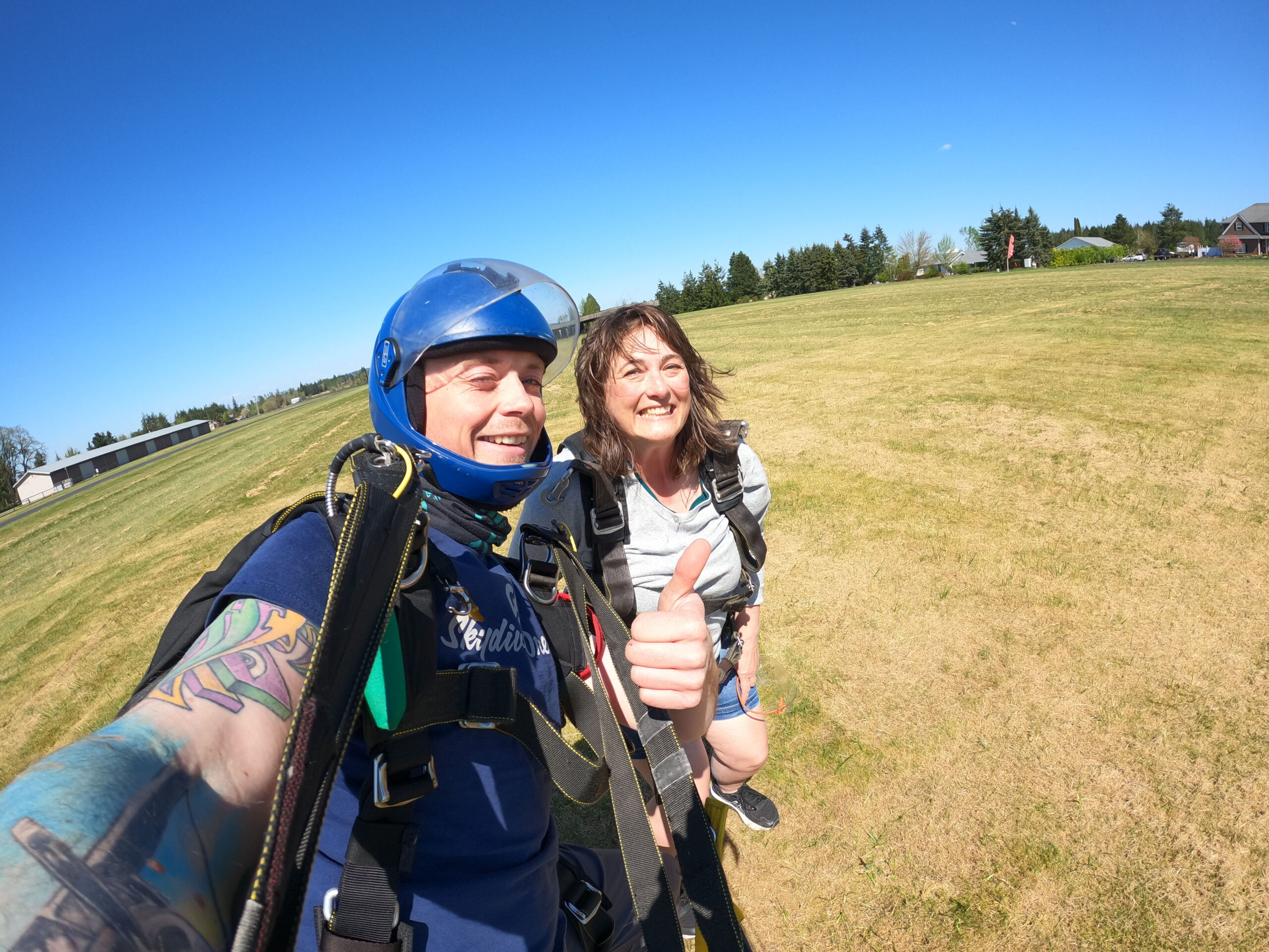 Guy and gal smiling for picture after landing on ground from skydiving.