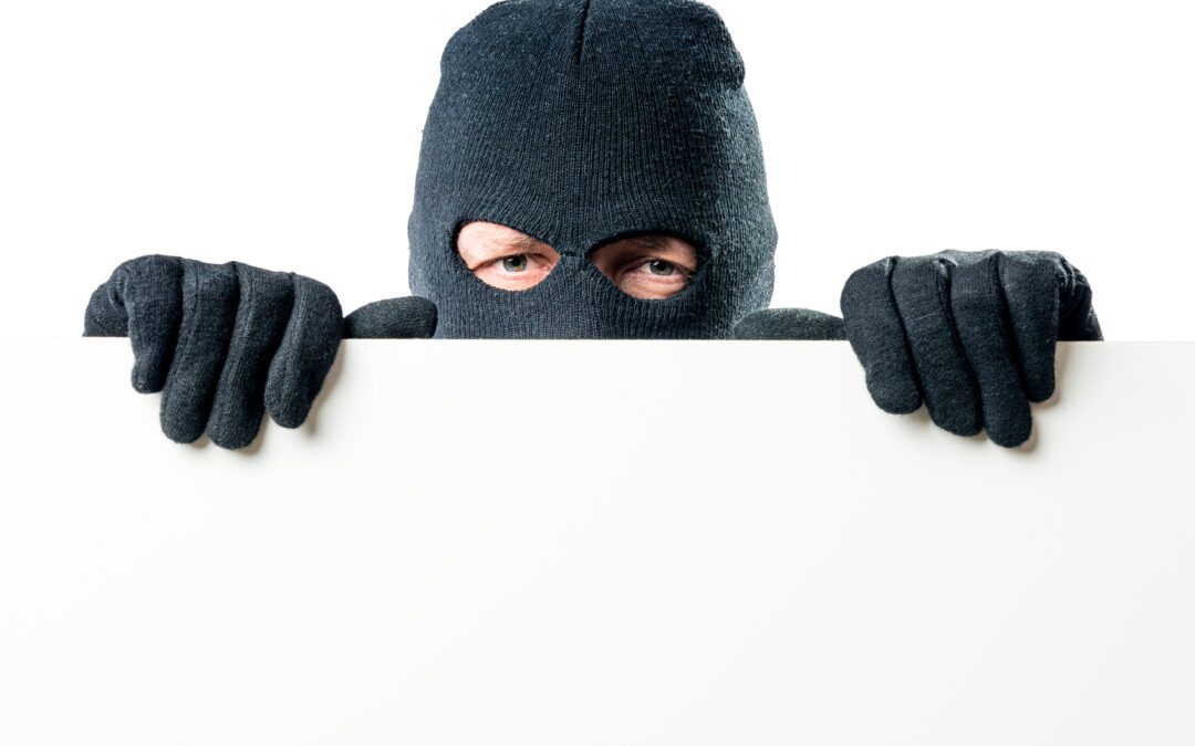 A masked person hiding behind a white wall