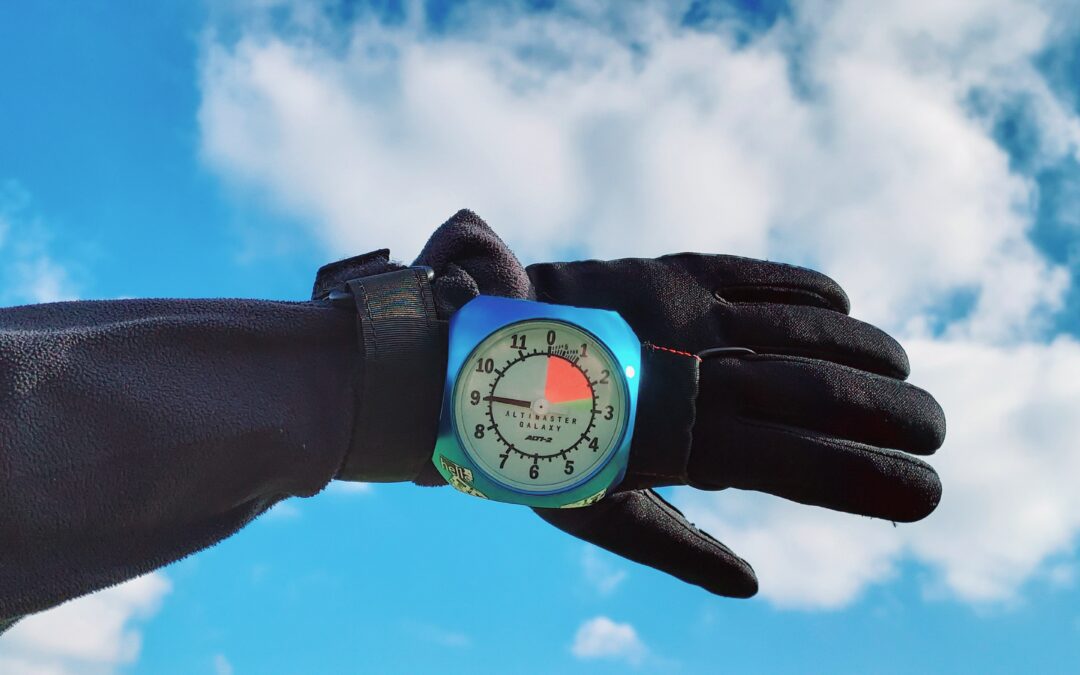 Blue sky with white clouds and a Gloved hand with altimeter reading nine thousand feet