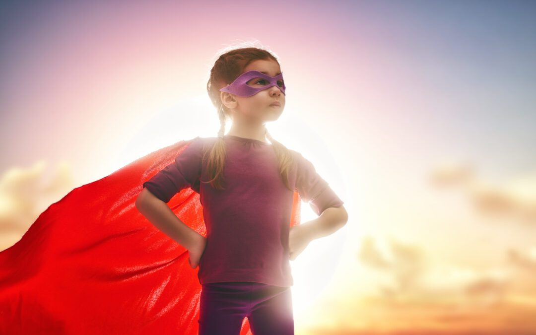 girl with red cape standing in the sunset.