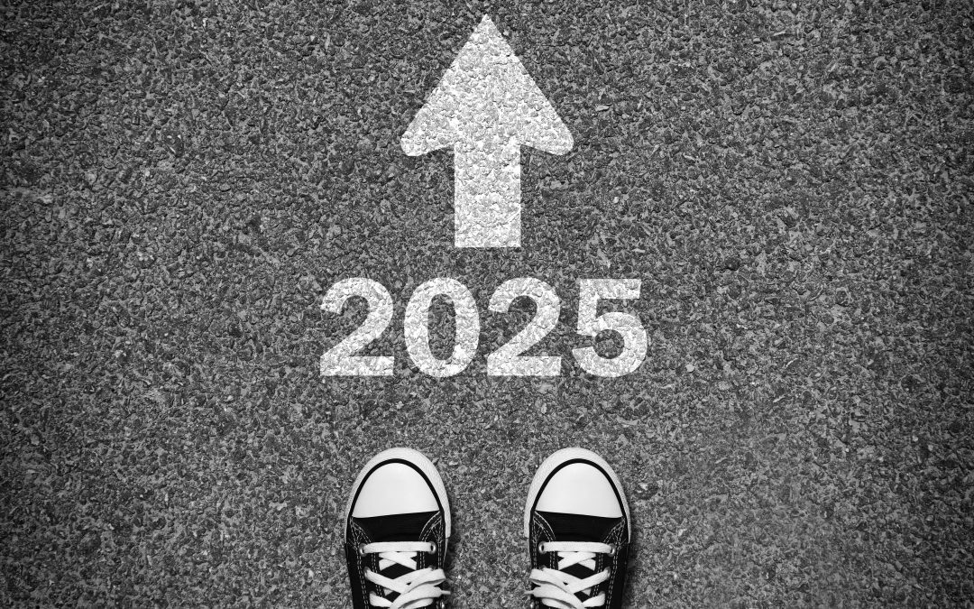 Pair of tennis shoes with 2025 and an arrow on a pavement.